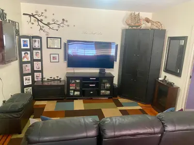a living room with a couch and a flat screen tv at Woodside room in Sunnyside