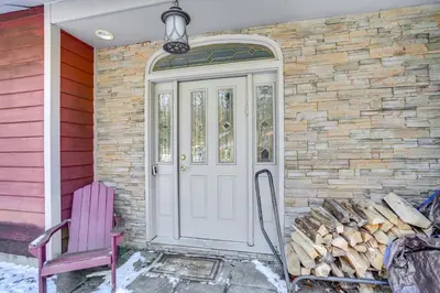 a house with a white door and a pile of fire wood at Less Than 1 Mi to Hunter Mtn Spacious Home with Hot Tub! in Lanesville
