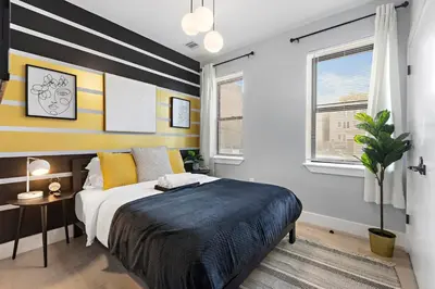 a bedroom with a large bed with yellow and white stripes at 4 Suites Near Downtown Newark in Newark