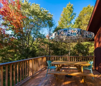 a wooden deck with a picnic table and an umbrella at Retro Retreat Charming Home with Hot Tub & Fire Pit in Rensselaer