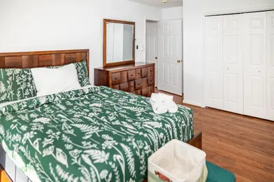 a bedroom with a bed with a green blanket and a mirror at Spacious 3BR House, Hot Tub, Firepit, Ski Access! in Emerald Lakes