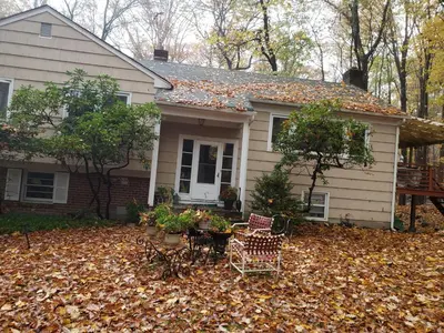 a house with leaves on the ground in front of it at Spacious Room with a View of the Woods in Armonk