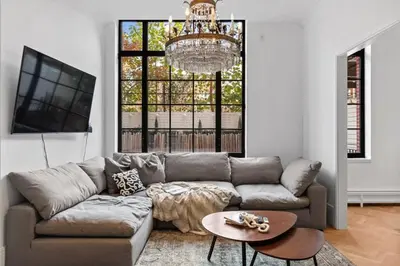 a living room with a couch and a chandelier at Clinton by Rove Travel 3BR Duplex with Backyard in New York