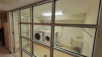 a laundry room with a washer and dryer behind glass at Cypress Court I by Rove Travel 2BR Harlem Apartment in New York