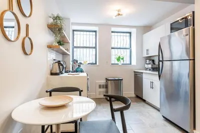 a kitchen with a table and a refrigerator at Cypress Court I by Rove Travel 2BR Harlem Apartment in New York