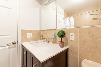 a bathroom with a sink and a potted plant at Cypress Court I by Rove Travel 2BR Harlem Apartment in New York