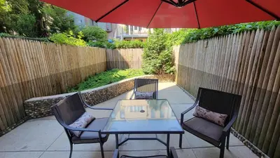 a patio with two chairs and a table and an umbrella at Cypress Court I by Rove Travel 2BR Harlem Apartment in New York