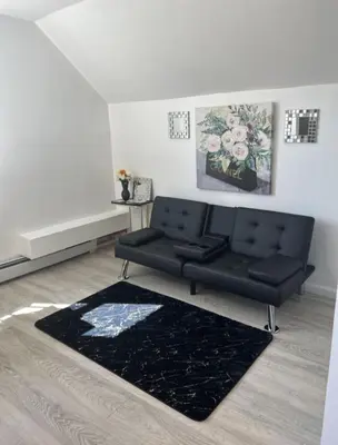 a living room with a black couch and a rug at Keri APRN LLC in Ansonia