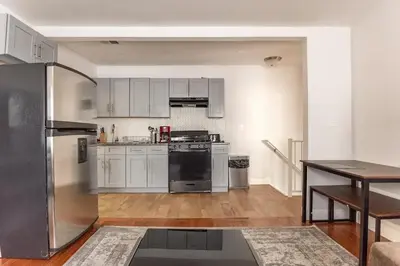 a kitchen with stainless steel appliances and a table at Spacious Cozy Retreat, Sleeps 10, Near NYC & EWR in Newark