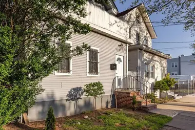 a white house with a tree in front of it at Spacious Cozy Retreat, Sleeps 10, Near NYC & EWR in Newark