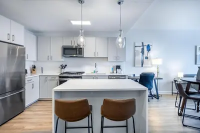 a kitchen with white cabinets and a large island with chairs at Luxury Modern Apt with Pool in Stamford