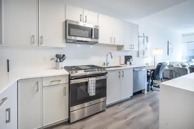a white kitchen with a stove and a microwave at Luxury Modern Apt with Pool in Stamford