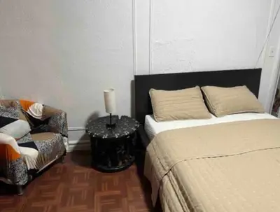 a bedroom with a bed and a chair and a lamp at Large and spacious room facing a beautiful park minutes away from Manhattan in High Bridge