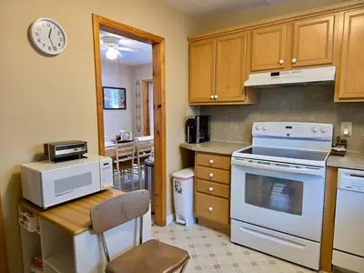 a kitchen with white appliances and a table with a clock at Charming, Pet-friendly Lake front Retreat WiFi in Ferndale