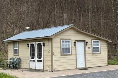 a small shed with two doors and a table and chairs at Cozy Cottage in the Catskills! in Oak Hill