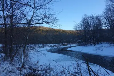 a river with snow on the ground and trees at The Glow Room at Indian Hollow in Chesterfield