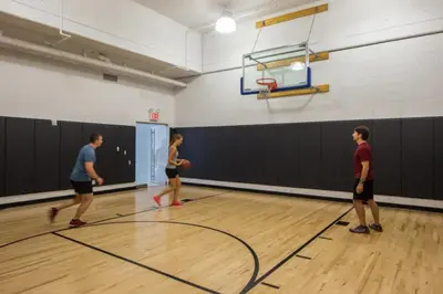 three people playing a game of basketball in a gym at Hells Kitchen 1BR w Doorman nr Central Park NYC-521 in New York