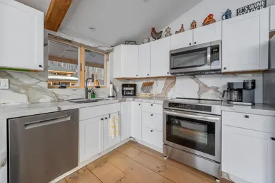 a kitchen with white cabinets and stainless steel appliances at Catskills Mountain Retreat - Luxury Meets Serenity in Jewett