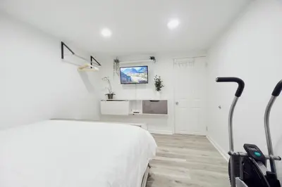 a white bedroom with a large bed and a staircase at 3BR Private Apt near LGA, JFK, Manhattan, Northern Blvd in Jackson Heights