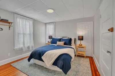 a bedroom with a bed with blue sheets and a rug at West Hartford Center- Charming New England Apt in West Hartford