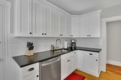 a kitchen with white cabinets and a black counter top at West Hartford Center- Charming New England Apt in West Hartford