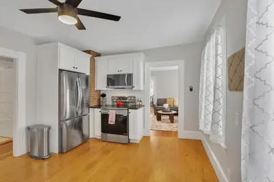 a kitchen with white cabinets and a stainless steel refrigerator at West Hartford Center- Charming New England Apt in West Hartford