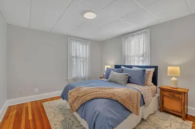 a bedroom with a blue bed and two windows at West Hartford Center- Charming New England Apt in West Hartford