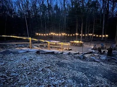 a group of tables and lights in a forest at night at Luxury Woodstock Retreat Hot tub heated pool in Woodstock