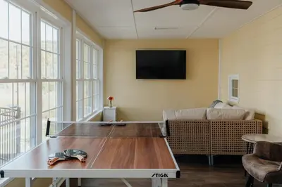 a living room with a table and a couch at Majestic views Hot tub Firepit Games Sleeps 14 in Hillsdale