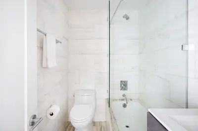 a white bathroom with a toilet and a shower at 73-1509 New Studio UWS Doorman Gym in New York