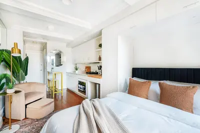 a white bedroom with a bed and a kitchen at 73-1509 New Studio UWS Doorman Gym in New York