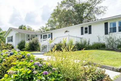 a white house with a garden in front of it at The Yuzu stunning mountain retreat with hot tub in Gardiner