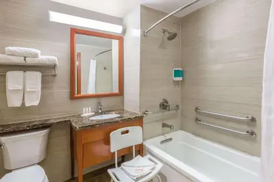 a bathroom with a tub and a toilet and a sink at Ramada by Wyndham Flushing Queens in Queens