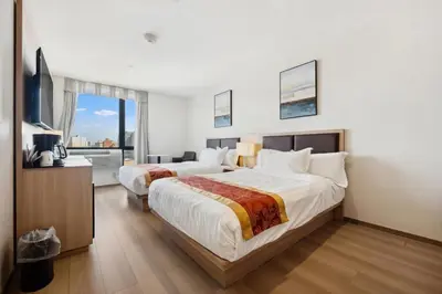 a hotel room with two beds and a television at Ramada by Wyndham Flushing Queens in Queens