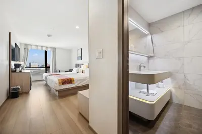 a white bathroom with a bed and a sink at Ramada by Wyndham Flushing Queens in Queens