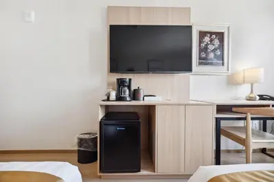 a hotel room with a desk with a television at Ramada by Wyndham Flushing Queens in Queens