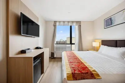 a hotel room with a bed and a large window at Ramada by Wyndham Flushing Queens in Queens