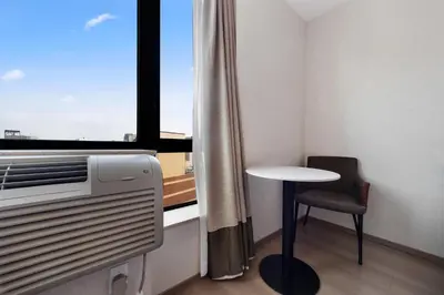 a small table and chair in a room with a window at Ramada by Wyndham Flushing Queens in Queens
