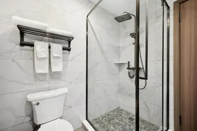 a white bathroom with a shower and a toilet at Ramada by Wyndham Flushing Queens in Queens