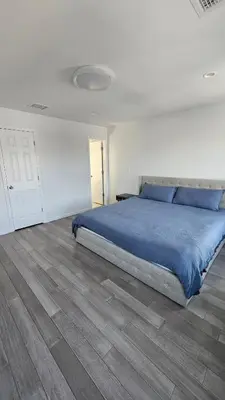 a bedroom with a blue bed and a wooden floor at 3 Bedroom Renovated Model House in New Hyde Park
