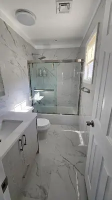 a bathroom with a toilet and a glass shower at 3 Bedroom Renovated Model House in New Hyde Park