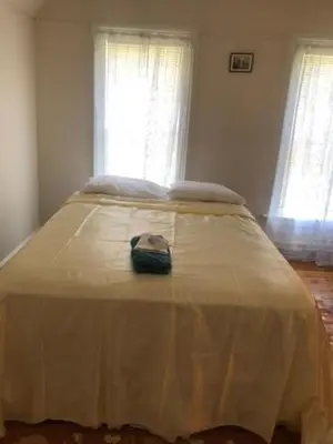 a large bed in a bedroom with two windows at Home Support And Care LLC in Binghamton