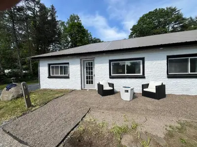 a white house with black windows and chairs at Twin Pines Lake resort 2 in Northville