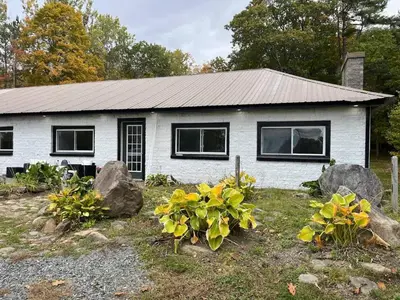 a white house with black windows and some rocks at Twin pines 3 in Northville