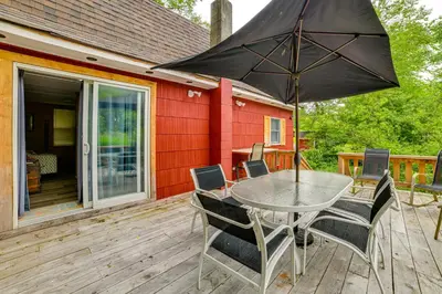 a table with chairs and an umbrella on a deck at Mtn-View Deck and Grill Creekside Catskills Cabin! in Equinunk