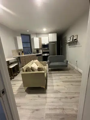 a living room with a couch and a kitchen at Adam Clayton Apartment in New York
