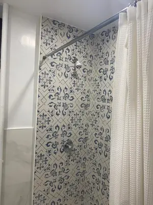 a bathroom with a shower with a blue and white tiles at Adam Clayton Apartment in New York