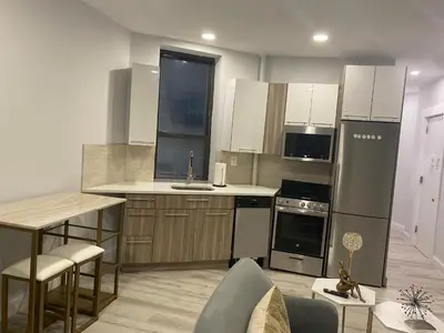a kitchen with stainless steel appliances and a table at Adam Clayton Apartment in New York