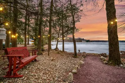 a red bench sitting next to a body of water at Lakehouse with Boats, MiniGolf, Sauna, HotTub, Swings and Playground! in Pocono Summit