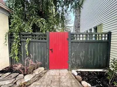 a red door on a house with a fence at Bright, Airy Home in Hudson! in Hudson